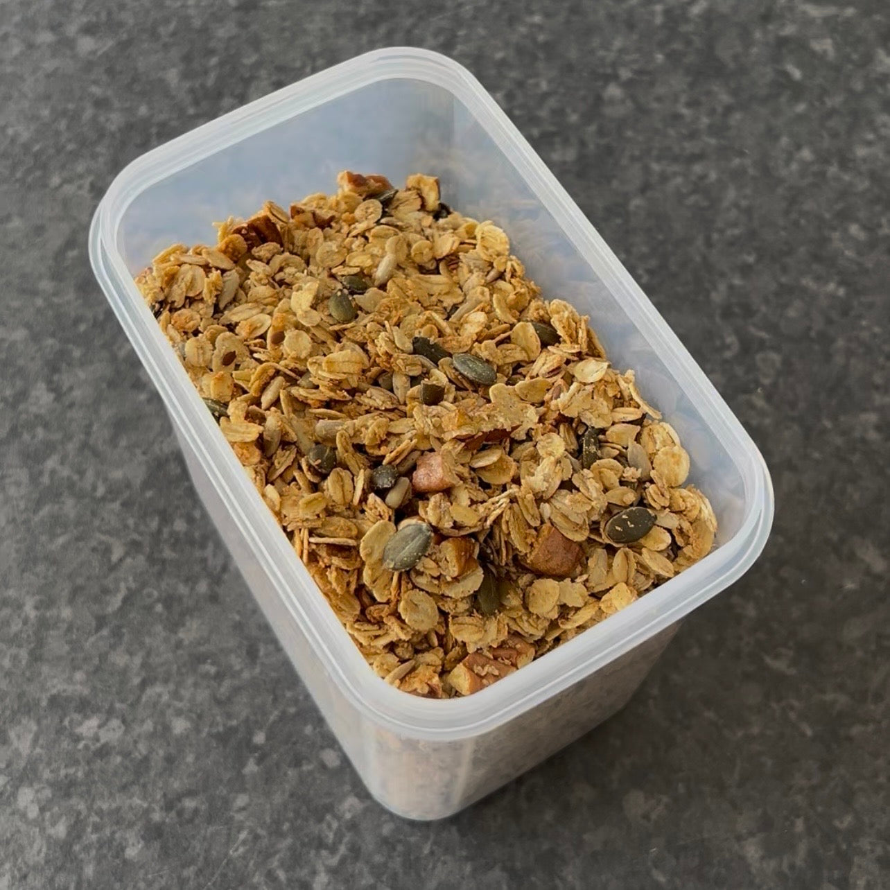Golden homemade granola with oats, pumpkin seeds, sunflower seeds and coconut served in a bowl with yogurt