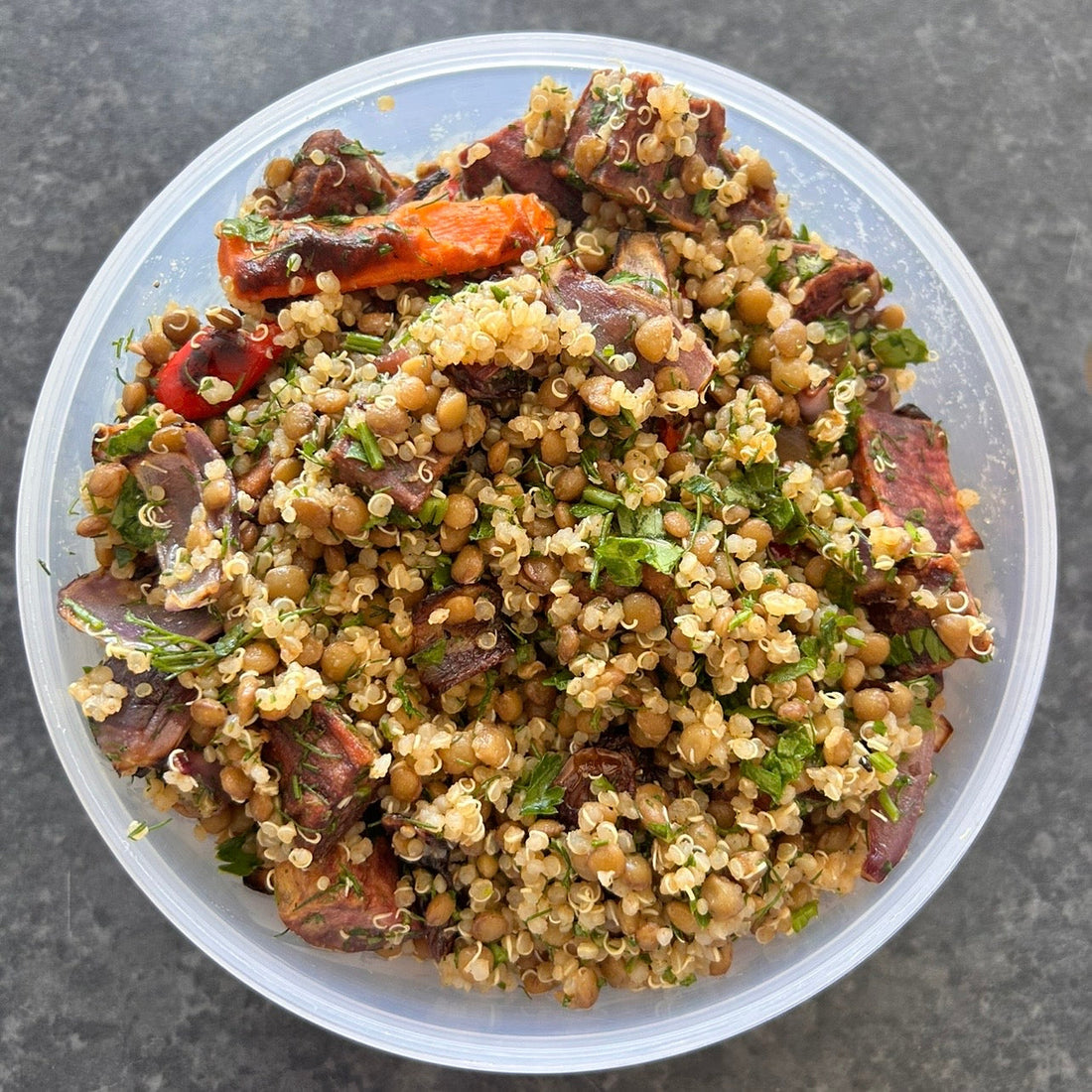 Roasted vegetable quinoa and lentil salad with herbs and lemon dressing served in a bowl.