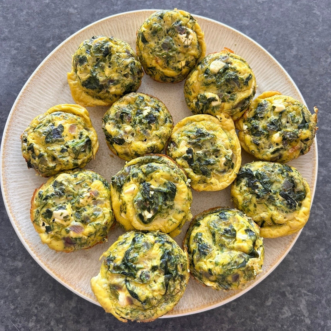 Mediterranean egg muffins with spinach, feta and herbs baked in a muffin tray.
