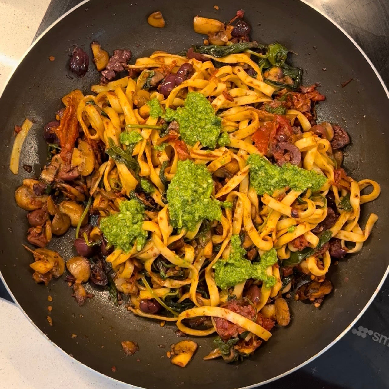 Mediterranean pesto pasta with mushrooms, spinach, olives and avocado.
