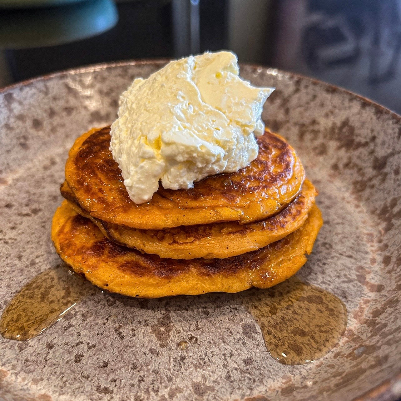 Stack of fluffy sweet potato pancakes topped with maple syrup and fresh fruit.